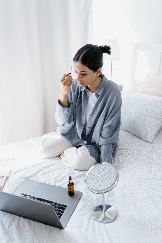 A woman sitting on the bed looking at her phone.