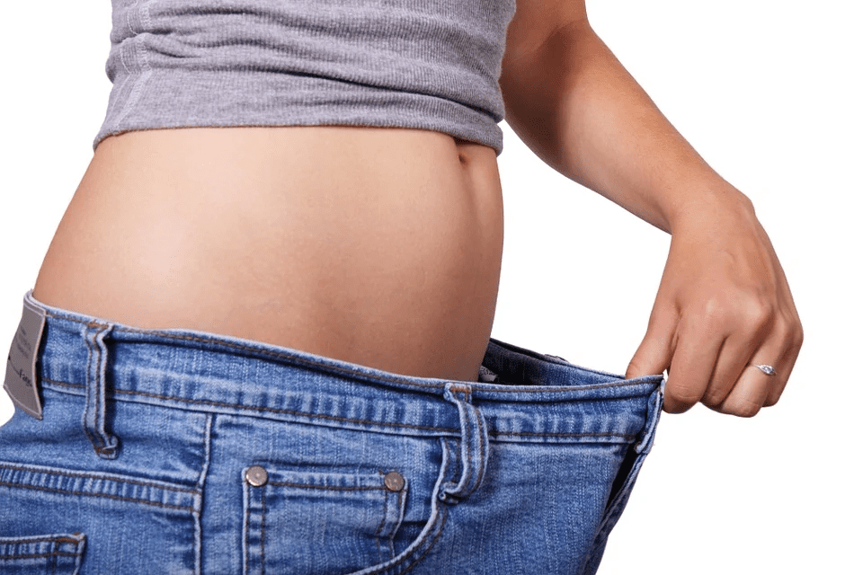 Women holding her jeans on her waist showing weight loss